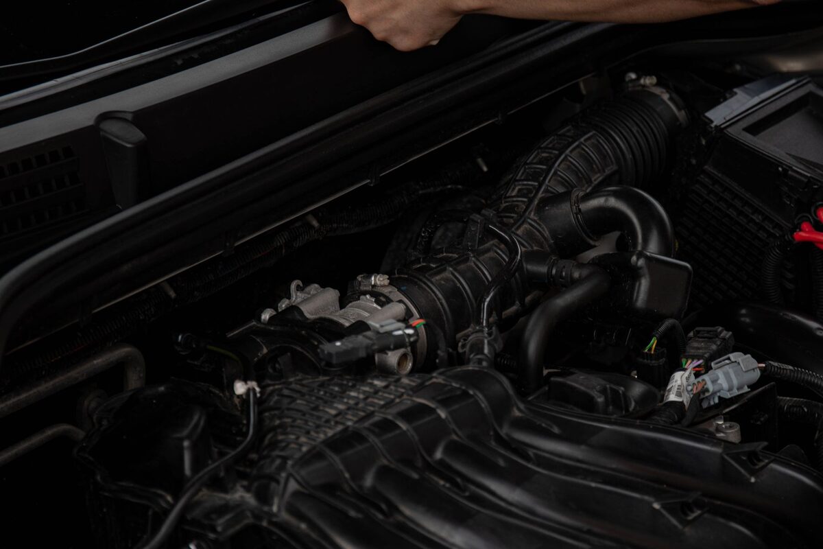 Hands working under a vehicle bonnet